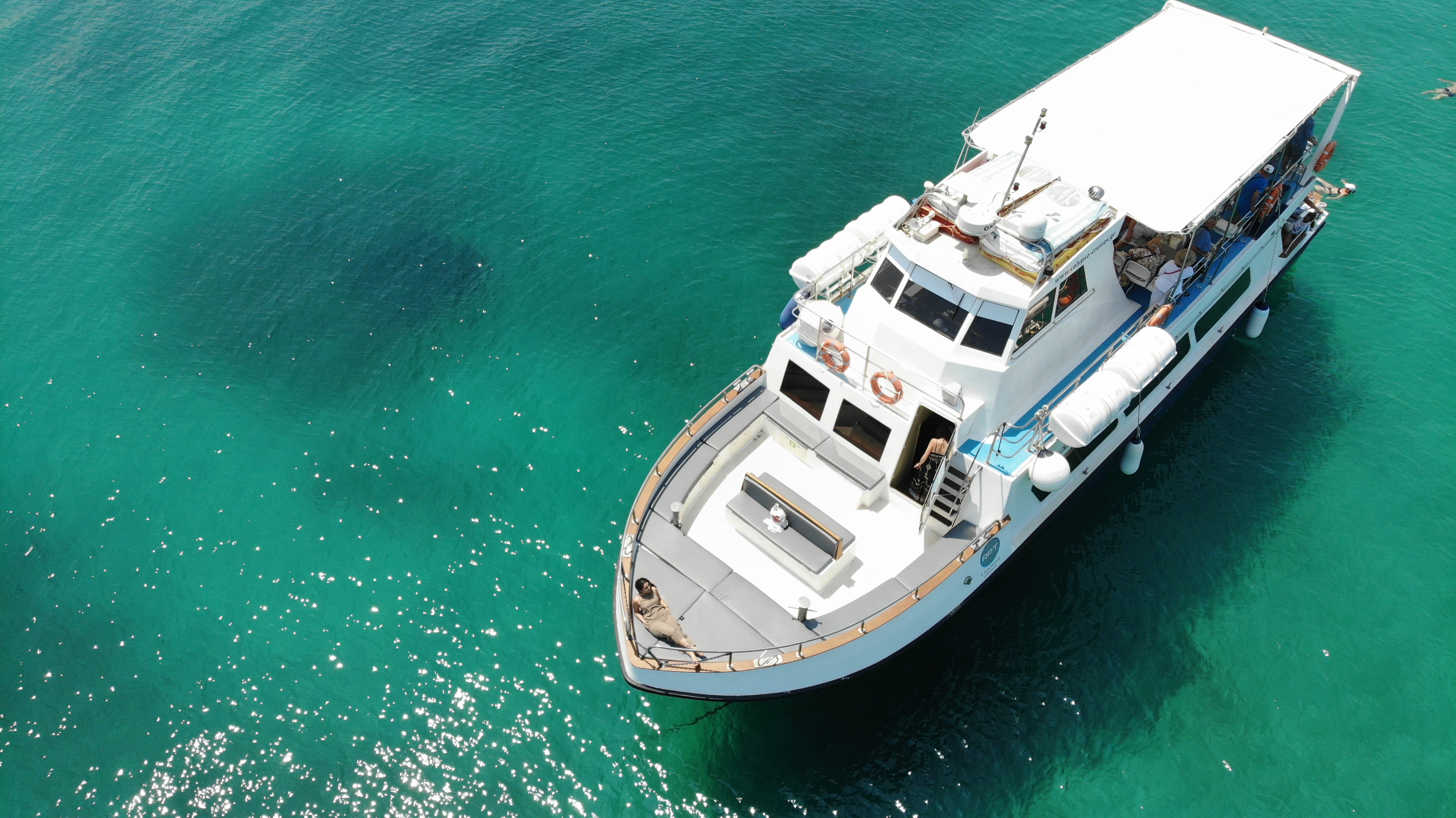Das Ausflugsboot von Calypso Cruises Ouranoupoli gleitet während einer Bootsfahrt ab Ouranoupoli mit einem griechischen Mittagessen auf dem leuchtend türkisfarbenen Wasser der Blauen Lagune.