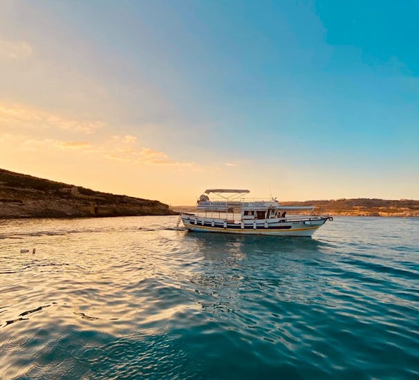 Personen machen eine Bootstour bei Sonnenuntergang von Gozo zur Blauen Lagune und zu den Höhlen von Comino mit Xlendi Pleasure Cruises