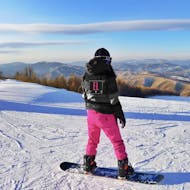 A woman looking at the mountains during her Private Snowboarding Lessons for Kids (from 5 y.) & Adults of All Levels - Belle Plagne from ELPRO Ski School La Plagne.