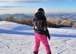 A woman looking at the mountains during her Private Snowboarding Lessons for Kids (from 5 y.) & Adults of All Levels - Belle Plagne from ELPRO Ski School La Plagne.