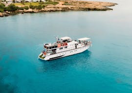 Boat of The Cyprus Cruise Company, navigating in clear blue waters during the Trip from Protaras to Blue Lagoon with Swimming Stops & BBQ.