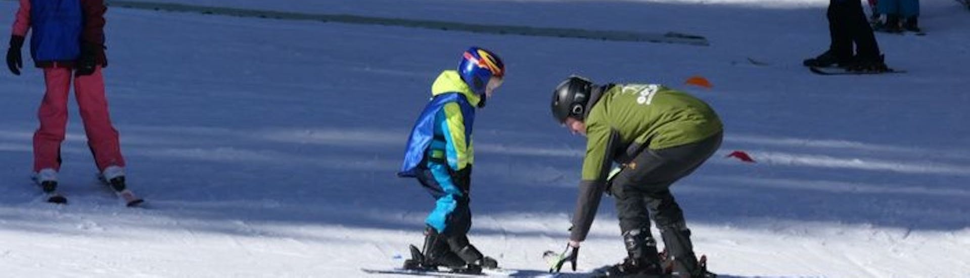 Ein kleiner Skifahrer und ein Skilehrer beim Kinder-Skikurs (ab 4 J.) für alle Levels.
