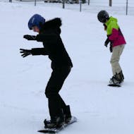 Zwei Kinder üben während ihrem Snowboardkurs für Kinder (ab 4 J.) & Erwachsene aller Levels mit Skischule Schneider Events Geißkopf.