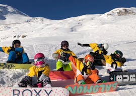 Eine Gruppe Kinder sitzt im Schnee während dem Snowboardkurs für Kinder (ab 7 J.) & Erwachsene für Anfänger mit Schweizer Ski- und Snowboardschule Arosa.