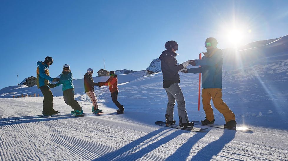Schüler üben gemeinsam während dem Snowboardkurs für Kinder (ab 7 J.) & Erwachsene für Fortgeschrittene.