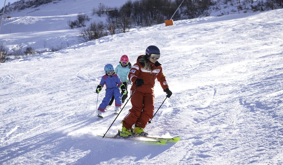 A ski instructor and two little skiers during their Kids Ski Lessons (3-13 y.) for Beginners.