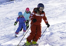 Eine Skilehrerin und zwei kleine Skifahrer während dem Kinder-Skikurs (3-13 J.) für Anfänger mit Official Swiss Ski School Rougemont Gstaad.