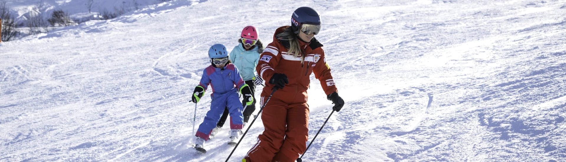 Eine Skilehrerin und zwei kleine Skifahrer während dem Kinder-Skikurs (3-13 J.) für Anfänger.