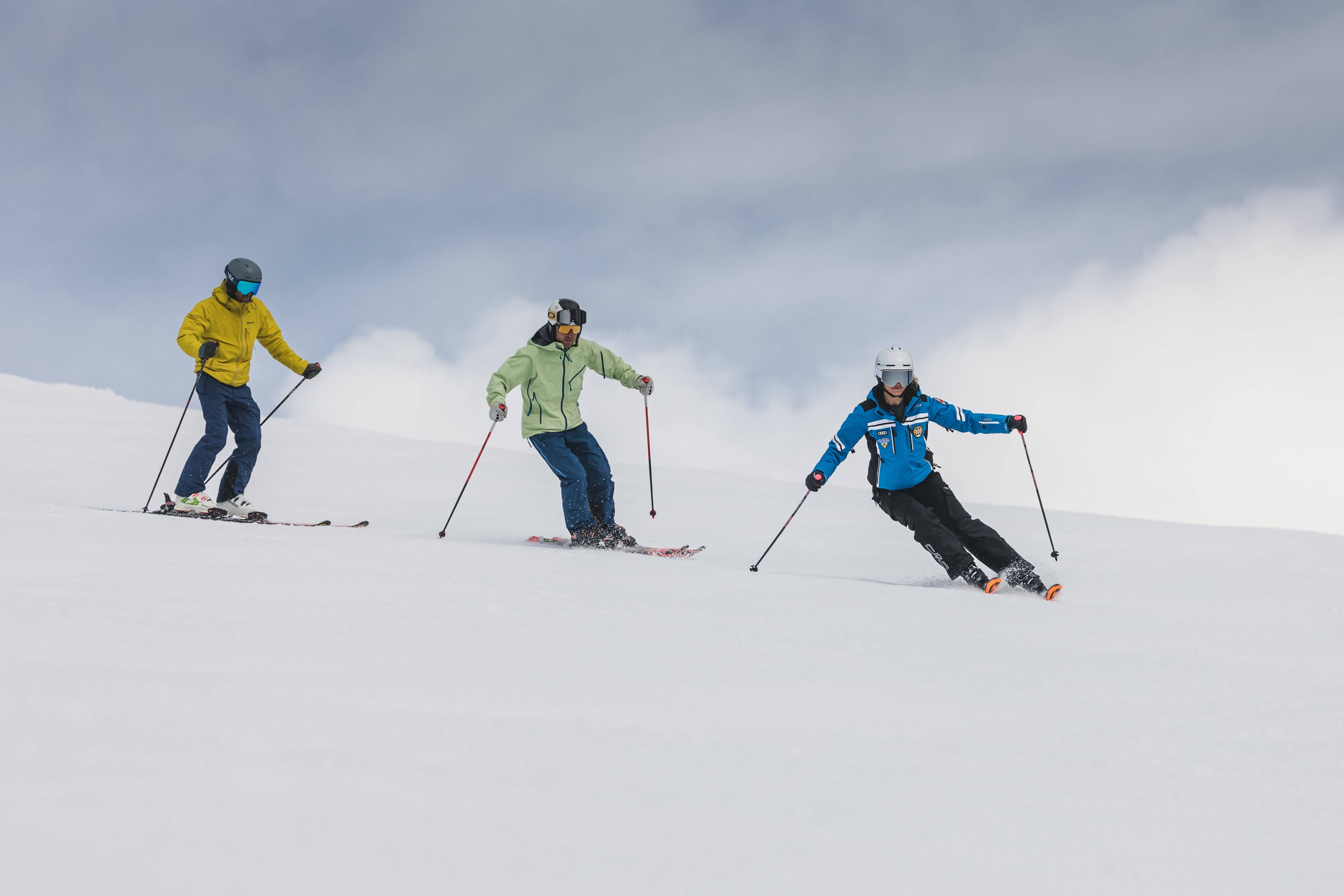Deux adultes prenant une leçon de ski avec un moniteur.