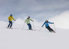Deux adultes prenant une leçon de ski avec un moniteur.