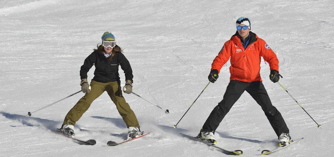 Ein Skianfänger und ein Skilehrer während dem Skikurs für Erwachsene Anfänger.