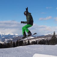 A snowboarder trying a jump during the Snowboarding Lessons for Kids (7-14 y.) 'Young Boarder Zone 2' for Advanced Boarders from BOARDat Saalbach-Leogang.