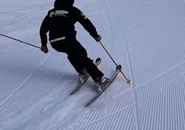 The ski instructor skis behind an adult skier during the Private Ski Lessons for Adults of All Levels from Feldberg Sports.