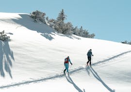 Two participants enjoying a sunny day in the snow during their Private Ski Touring Guide for All Levels from Hansi Kienle.