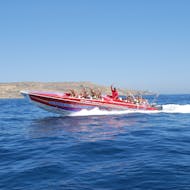 A group of people smiling and waving out of the motor boat during the Power Boat Trip from Sliema to the Blue Lagoon and Comino Caves from Supreme Powerboats Sliema.