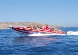 A group of people smiling and waving out of the motor boat during the Power Boat Trip from Sliema to the Blue Lagoon and Comino Caves from Supreme Powerboats Sliema.