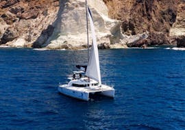 A Catamaran on the sparkling blue water at the Catamaran Trip in Santorini with BBQ, Open Bar & Swimming from Volcano Yachting Santorini.