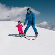 Ein Kind und ein Skilehrer lächeln beim Privatern Kinder-Skikurs (ab 1 J.) für alle Levels mit Skischule Bruck Fusch.