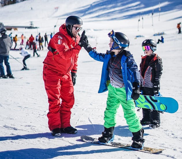 Bild von zwei Kindern mit ihrem Lehrer während einer privaten Snowboardstunde bei Neige Aventure.