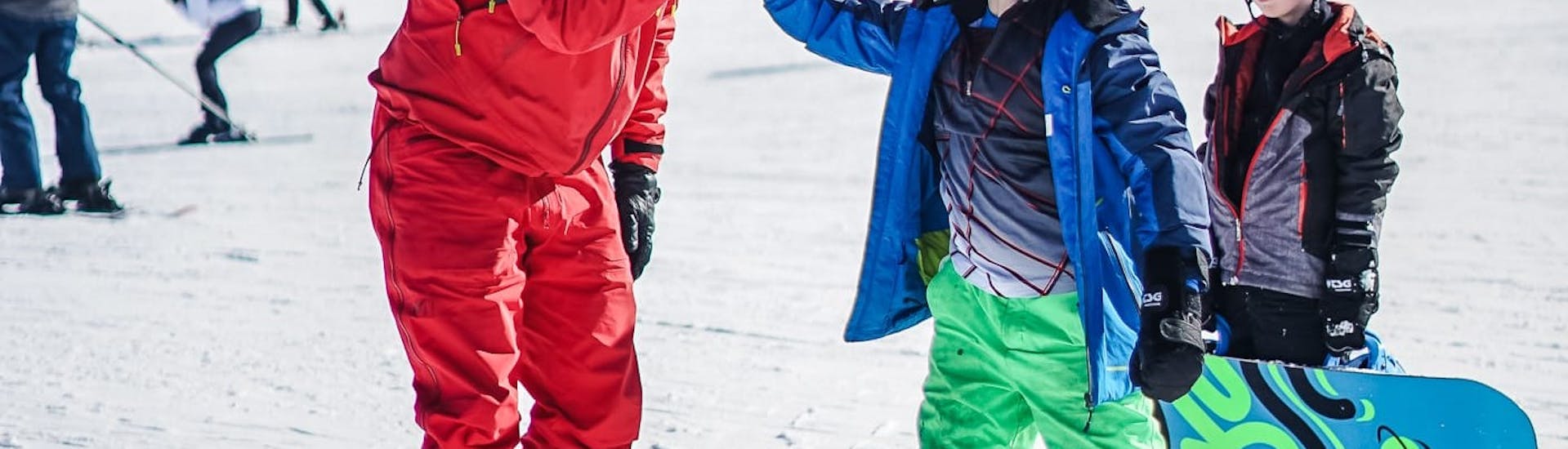 Bild von zwei Kindern mit ihrem Lehrer während einer privaten Snowboardstunde bei Neige Aventure.
