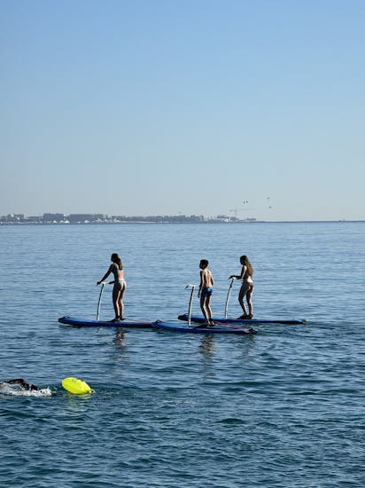 trois jeunes sur des paddles Black Tenders, en train de naviguer sur des eaux de couleur turquoise, sous le soleil.