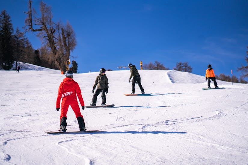 Bild von 3 Freunden mit ihrem Lehrer während einer Snowboardstunde bei Neige Aventure.
