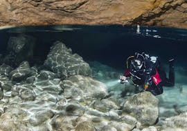 A person diving in a cave with an underwater torch during the Guided boat and shore dives around Malta, Comino and Gozo island for certified divers from Dive Vision Malta with the provider Dive Vision.