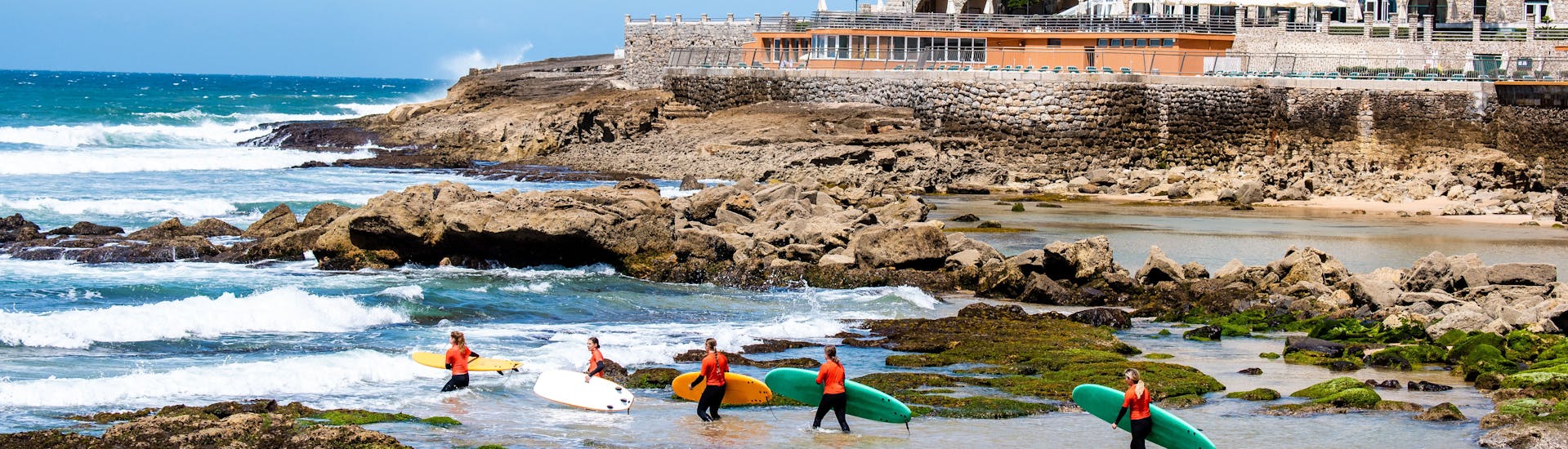 A group of people set off to go surfing while Surf Lessons (from 12 y.) on the Matadoura Beach in Ericeira organized by SeaKrew Ericeira.