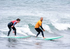 The surf instructor is surfing together with a student while Private Surf Lessons (from 12 y.) on the Matadouro Beach in Ericeira organized by SeaKrew Ericeira.