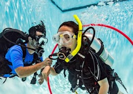 An instructor teaching a young girl things underwater during the Private trial diving course in Marfa Bay for children of 8-10 from Dive Vision Malta.