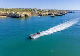AlgarExperience: un'esperienza in catamarano alla scoperta delle grotte costiere di Albufeira. Il catamarano AlgarExperience sfreccia sull'oceano blu lungo la costa rocciosa di Albufeira durante un tour in catamarano alla scoperta di delfini e grotte, accompagnato da un biologo marino.