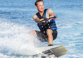A young man is Wakeboarding at Anassa Beach from Latchi Dive & Watersports Centre.