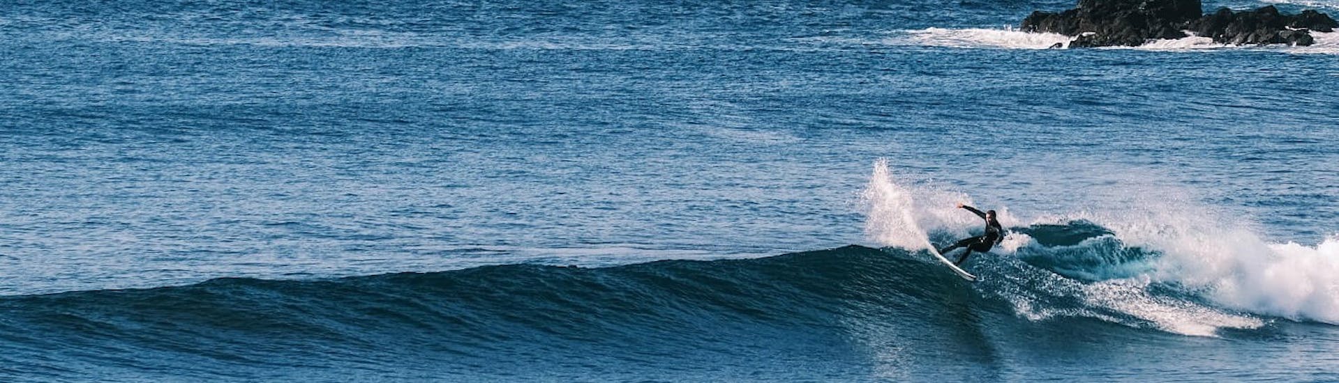 Ein Mann der eine Welle reitet bei seinen Surfkursen für Anfänger (ab 10 J.) auf den Azoren.
