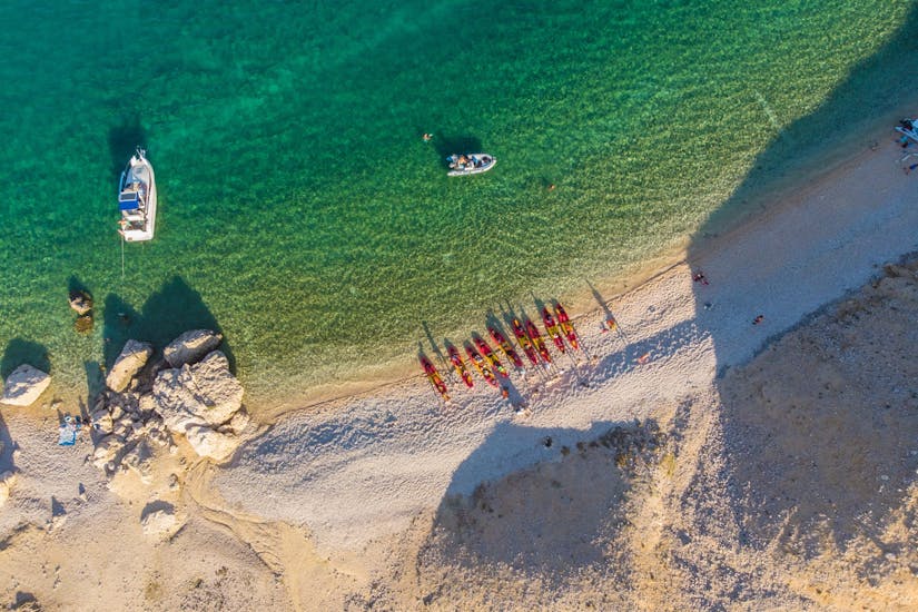 Een foto van boven met alle kajaks op het strand tijdens het zeekajakken in Pag Bay van Sunturist.