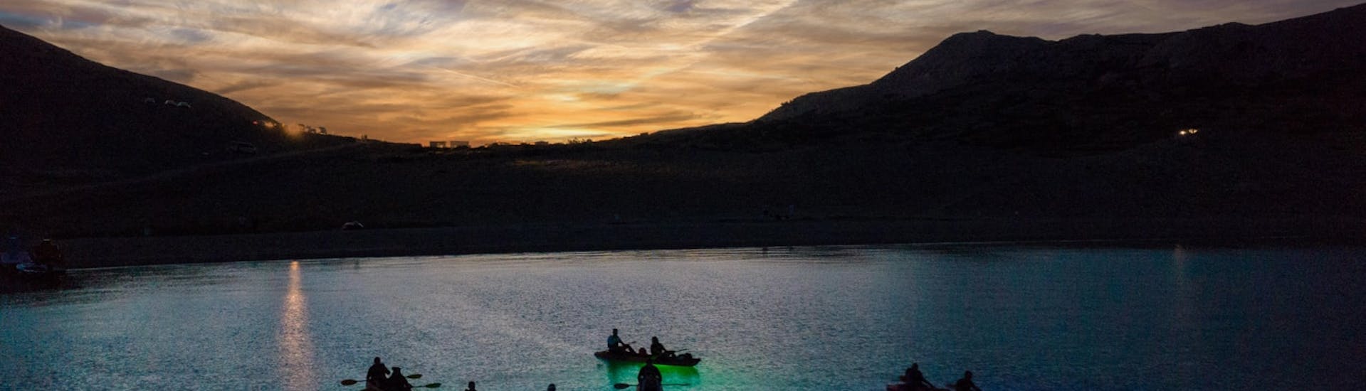 People kayaking with a nice view and with colourful lights under them during theNight Glow Kayaking tour in Pag Bay from Ručica Beach.