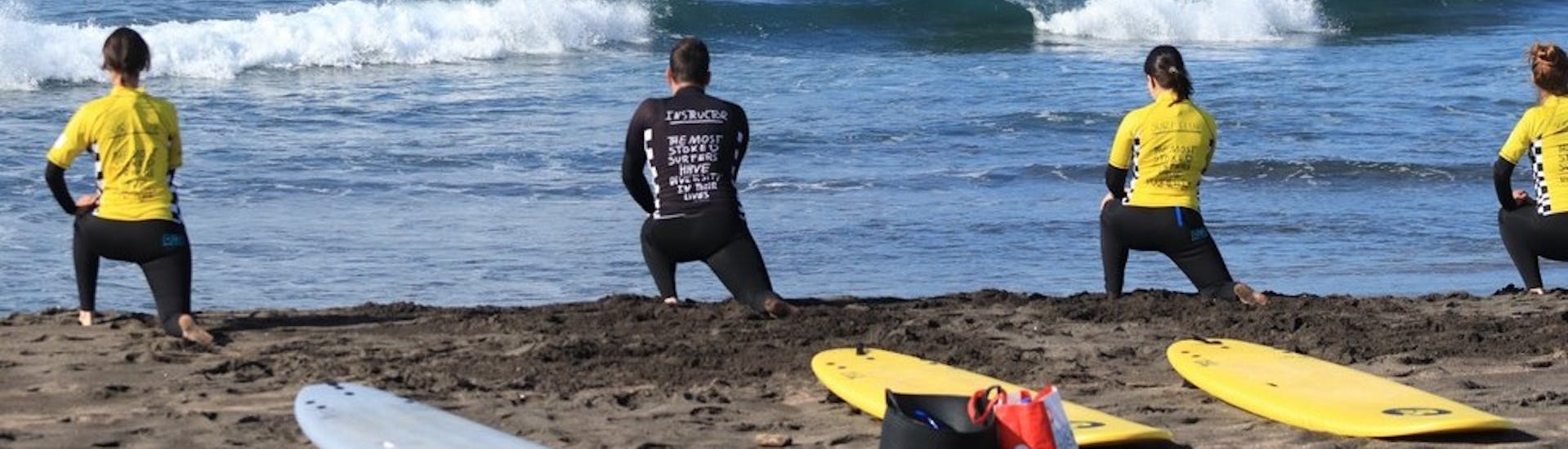 A group doing a Private Surfing Lessons (from 10 y.) in the Azores stretching at the beach.