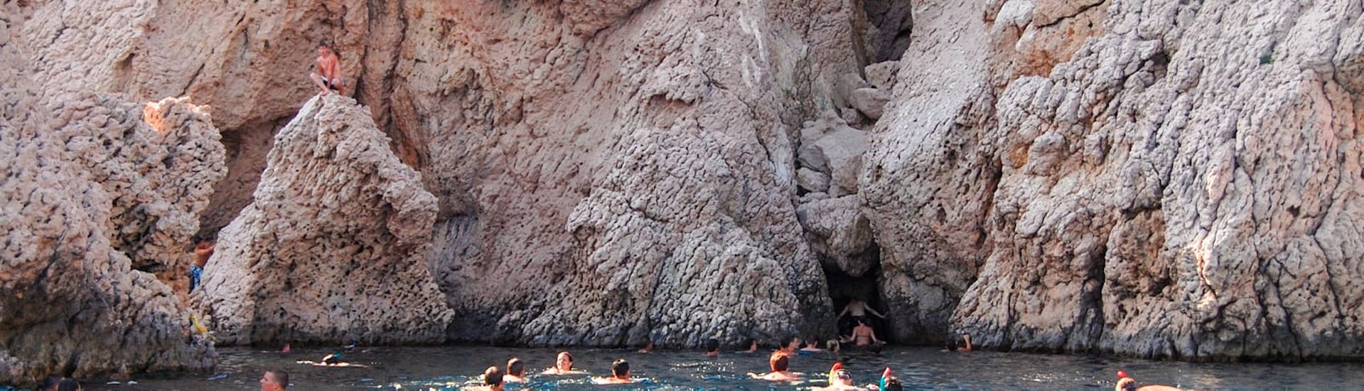 Mensen die zwemmen voor rotsen en grotten tijdens de  Boottocht in Pag Bay met Lunch en Zwemmen van Sunturist Novalja.