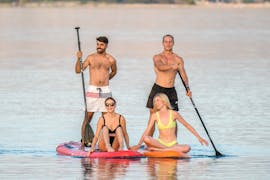2 couples who are supping, where the guys are peddling and the girls are sitting on the SUP board during the SUP Tour to Zrce Beach and Tunera from Sunturist Novalja.