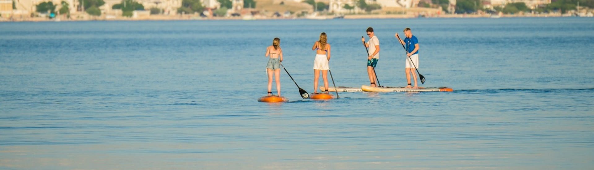 Two guys and 2 girls supping during the SUP Tour to Zrce Beach and Tunera from Sunturist Novalja.