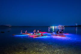 Mensen ontspannen op hun SUP boards met de kleurrijke verlichting tijdens de Nacht Glow SUP Tour naar Zrće Strand en Tunera met Sunturist.