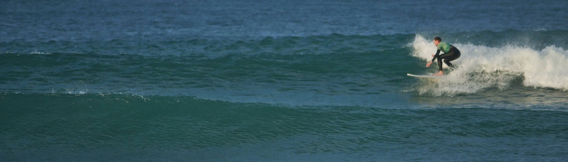 Un enfant prenant une vague grace à un cours de surf privée de G3 Store à Peniche (dès 8 ans)- Tout inclus.