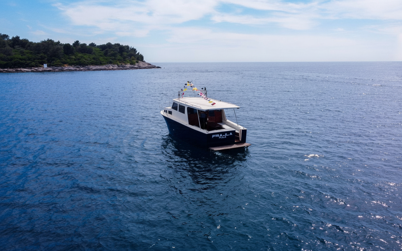El barco 'Frajla' de Pula Boat Tours Croatia navega sobre el mar azul y tranquilo cerca de una costa exuberante durante una excursión privada en barco desde Pula con paradas para practicar snorkel y nadar.