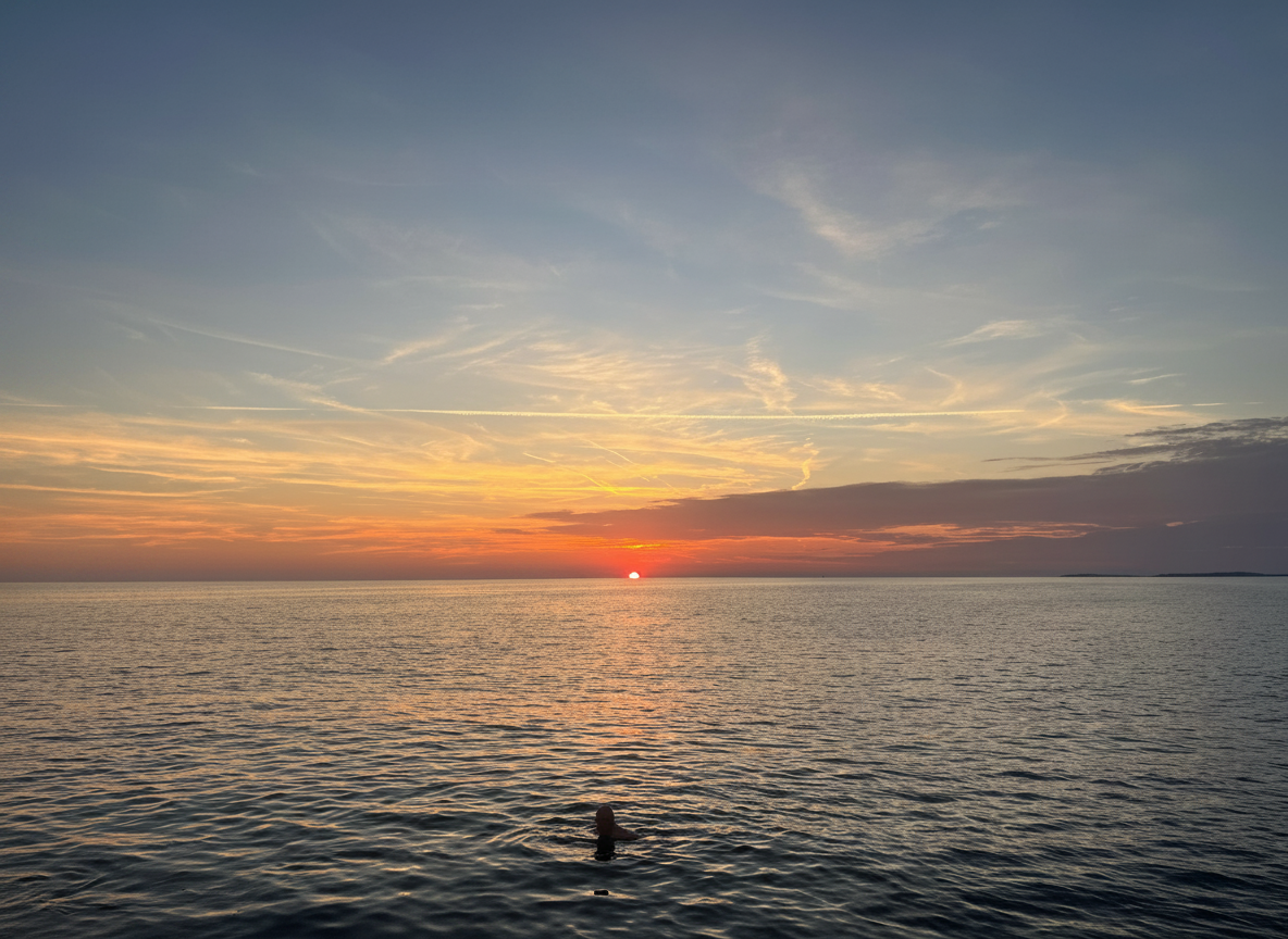 Una persona nada en el mar en calma mientras se pone el sol durante una excursión privada en barco desde Pula con paradas para practicar snorkel y natación, organizada por Pula Boat Tours Croatia.
