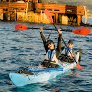 Zwei Teilnehmer jubeln auf ihrem Kajak während der Kajak-Tour in der Bucht von Kissamos mit Schwimmstop bei Sonnenuntergang mit Sea Kayak Kissamos.