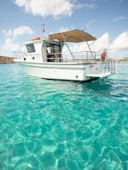 A boat is sailing on the crystal clear water while Private Boat Trip to Comino Island & Saint Mary´s Tower with Snorkeling organized by Aloha Boat Charters Malta.