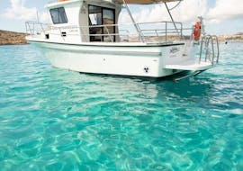 A boat is sailing on the crystal clear water while Private Boat Trip to Comino Island & Saint Mary´s Tower with Snorkeling organized by Aloha Boat Charters Malta.