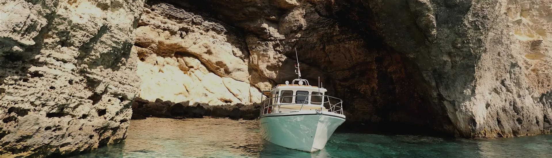 A boat is sailing through the caves while Private Boat Trip to Comino Island & Saint Mary´s Tower with Snorkeling organized by Aloha Boat Charters Malta.