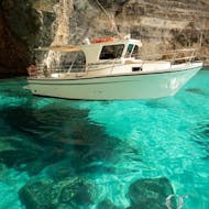 A boat is floating on crystal clear water while doing a Private Party Boat Trip to Blue Lagoon & Crystal Lagoon organized by Aloha Boat Charters Malta.