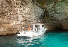 A boat is floating on the crystal clear water while doing a Private Boat Trip with Dinner & Swimming stops at Sunset organized by Aloha Boat Charters Malta.