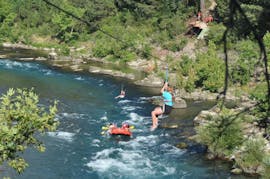 Rafts op de rivier en iemand is aan het ziplinen boven hun tijdens de Avontuur Combo: Raften, Zipline, Lunch, + Optionele Quad/Buggy/Jeep Rit met Tornado Rafting.
